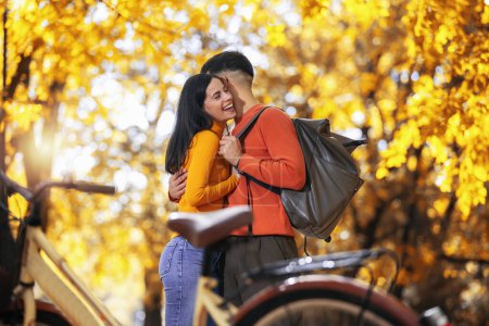 Téléchargez les photos : Heureux jeune couple en vélo par une journée ensoleillée d'automne. Le parc est coloré - en image libre de droit