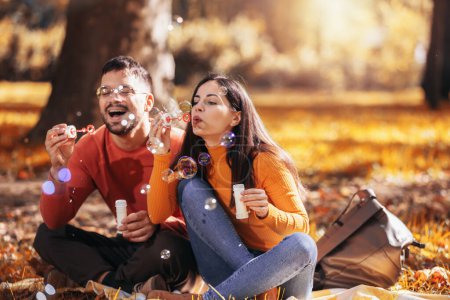Téléchargez les photos : Jeune couple relaxant dans le parc avec ventilateur à bulles. - en image libre de droit