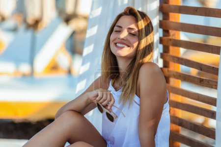 Photo for Beautiful young woman chilling on deck chair on the beach. - Royalty Free Image