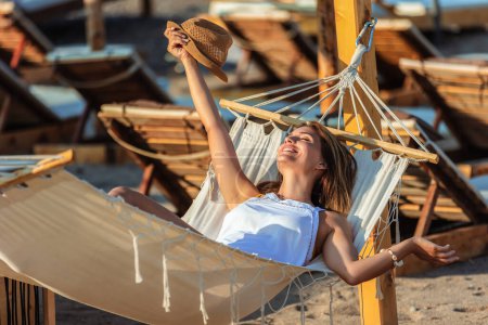 Photo for Beautiful young woman chilling on deck chair on the beach. - Royalty Free Image