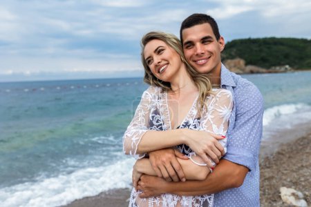 Téléchargez les photos : Heureux jeune couple smilling et câlins sur l 'plage. - en image libre de droit