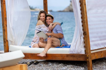 Téléchargez les photos : Jeune couple commandant quelque chose en ligne avec la carte, sur la plage - en image libre de droit