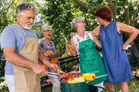 Photo for Elderly people are making barbeque, drinking beverages, making memories, and laughing. - Royalty Free Image