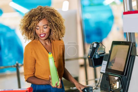 Photo for African American woman buying food at grocery store or supermarket self-checkout - Royalty Free Image