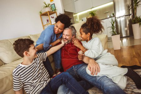 Photo for Young family watching TV together at home and having fun together. - Royalty Free Image