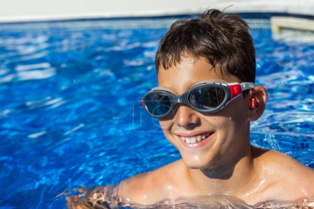 Photo for Little boy getting ready to swim in the pool, having ear plugs and goggles. Summer break vacation. - Royalty Free Image