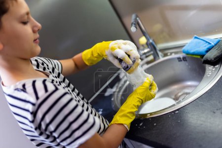 Téléchargez les photos : Enfant laver la vaisselle dans l'évier et s'amuser - en image libre de droit