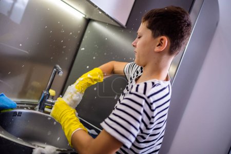 Foto de Niño lavar los platos en el fregadero y divertirse - Imagen libre de derechos