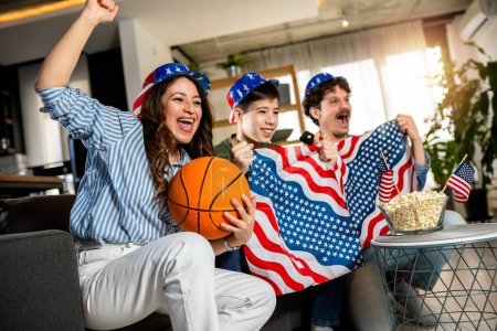 Téléchargez les photos : Latino famille regarde match de basket avec drapeau américain. - en image libre de droit