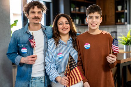 Foto de La familia latina votó en las elecciones. Sostiene bandera americana. - Imagen libre de derechos