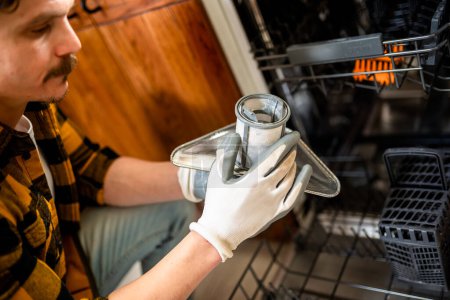 Photo for Latino man fixing dishwasher in the kitchen. - Royalty Free Image