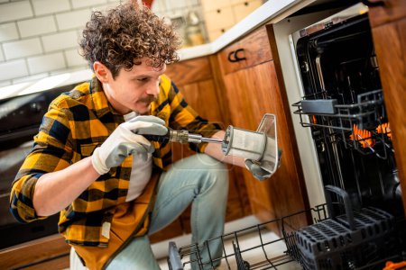 Foto de Hombre latino arreglando lavavajillas en la cocina. - Imagen libre de derechos