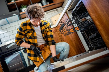 Photo for Latino man fixing dishwasher. - Royalty Free Image