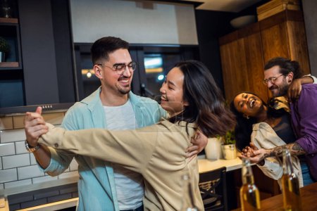 Téléchargez les photos : Des amis multiethniques avec des pizzas et des bouteilles de boissons faisant la fête. Danse et chant. - en image libre de droit