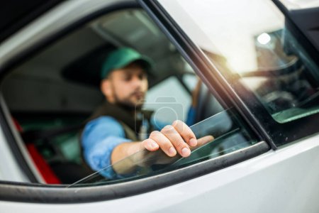Téléchargez les photos : Jeune chauffeur de camion roule vers le bas de la fenêtre. - en image libre de droit