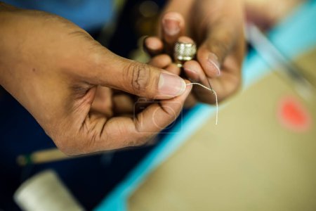 Photo for Young African American tailor sewing with a thread. - Royalty Free Image