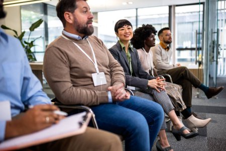 Téléchargez les photos : Groupe de gens d'affaires multiethniques à l'écoute de la conférence qui est dans leur entreprise. - en image libre de droit