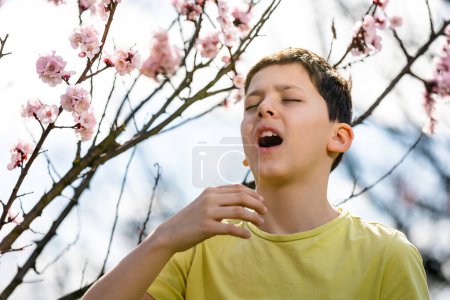 Téléchargez les photos : Enfant allergique au pollen. Garçon éternuer à cause d'une allergie saisonnière - en image libre de droit