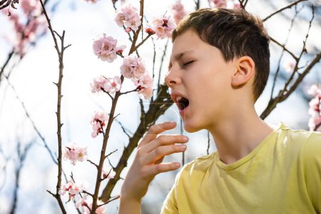 Téléchargez les photos : Enfant allergique au pollen. Garçon éternuer à cause d'une allergie saisonnière - en image libre de droit