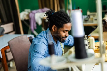 Foto de Joven sastre afroamericano coser con una máquina de coser en su propio taller - Imagen libre de derechos
