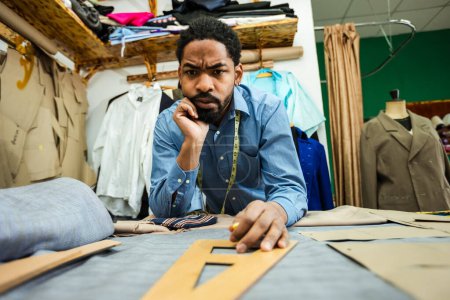 Photo for Male African American tailor measuring fabric with a ruler in his own atelier. - Royalty Free Image