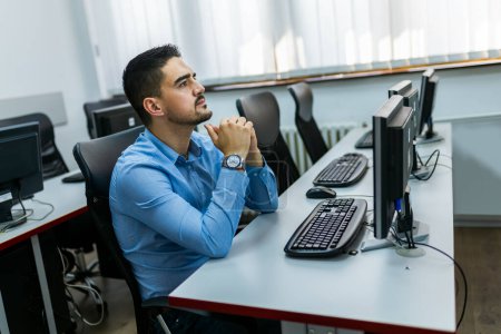 Téléchargez les photos : Étudiant masculin utilisant un PC de bureau en laboratoire informatique. - en image libre de droit