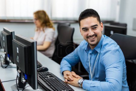 Téléchargez les photos : Jeune homme d'affaires beau travaillant dur sur son ordinateur dans son bureau - en image libre de droit