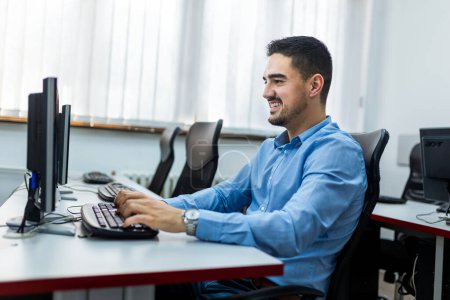 Foto de Estudiante masculino usando PC de escritorio en laboratorio de computación. - Imagen libre de derechos