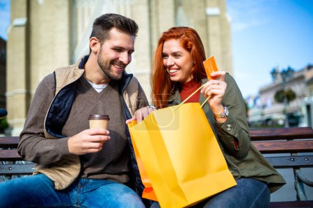 Téléchargez les photos : Portrait de couple heureux avec des sacs à provisions après avoir magasiné en ville en souriant et en tenant une carte de crédit - en image libre de droit