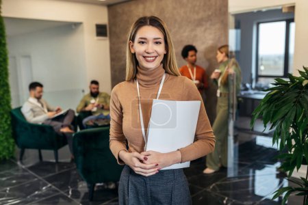 Photo for A business woman dressed casually is standing in the lobby of an office building in front of a business team - Royalty Free Image