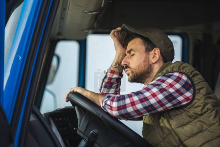 Foto de Un camionero cansado se toma un descanso de conducir y descansa en su camión - Imagen libre de derechos