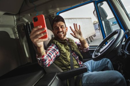 Téléchargez les photos : Conducteur masculin heureux et confiant assis dans son camion, utilisant son téléphone pour parler à quelqu'un - en image libre de droit