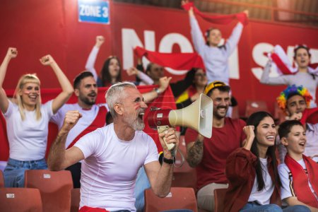 Photo for Football / soccer fans are cheering for their team at the stadium on the match. The cheer leader uses a megaphone - Royalty Free Image