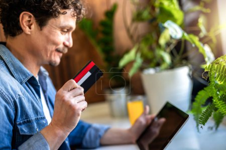 Photo for Latino man at home buying online. Using his card. - Royalty Free Image