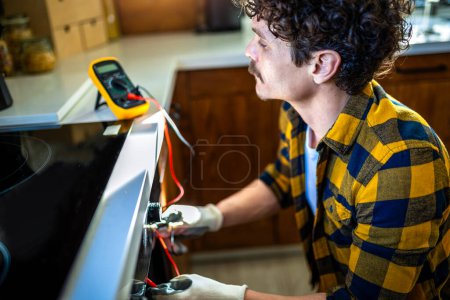 Photo for Latino man using multimeter for fixing stove. - Royalty Free Image