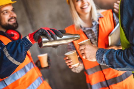  Drei Bauarbeiter machen Kaffeepause auf Baustelle