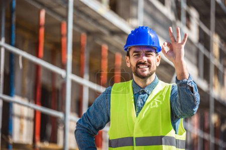 Photo for Construction site manager standing  wearing safety vest and helmet, thinking at construction site. Young architect watching construction site with confidence. - Royalty Free Image