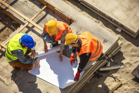 Photo for Top view, Team engineer building inspection looking at blueprint working at construction site. Civil Engineer, Contractor and Architect discussing in construction site. - Royalty Free Image