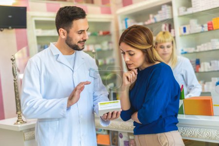 Téléchargez les photos : Pharmacien gai chimiste homme donnant des vitamines, des antibiotiques à la jeune femme dans la pharmacie moderne. - en image libre de droit