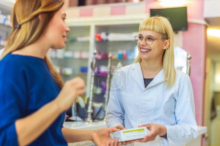 Photo for Cheerful pharmacist chemist woman giving vitamins, antibiotics to young woman in modern pharmacy. - Royalty Free Image