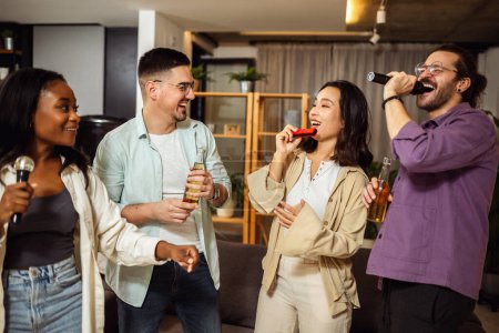 Téléchargez les photos : Groupe multiracial d'amis ayant nuit karaoké. Chanter au micro, boire de la bière et jouer de l'orgue. - en image libre de droit