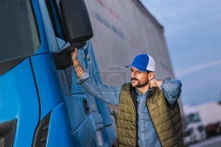 Müder männlicher Fahrer steht vor seinem LKW und streckt sich nach langer Fahrt aus