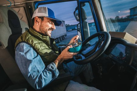 Téléchargez les photos : Chauffeur de camion prenant une pause de longue route pour manger de la nourriture du conteneur. - en image libre de droit