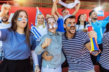 Photo for Greece fans cheering at the game on stadium. Wearing blue and white colors to support their team. Celebrating with flags and scarfs. - Royalty Free Image