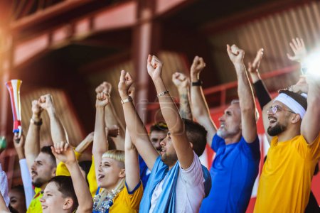 Téléchargez les photos : Gros plan des mains en l'air. Les fans de sport applaudissent au match sur le stade. Porter des couleurs jaunes et bleues pour soutenir leur équipe. Célébration avec drapeaux et foulards. - en image libre de droit