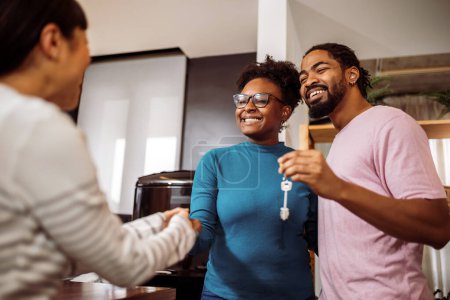 Téléchargez les photos : Couple afro-américain obtenir des clés de leur agent immobilier, pour leur nouvelle maison. Serrer la main. - en image libre de droit