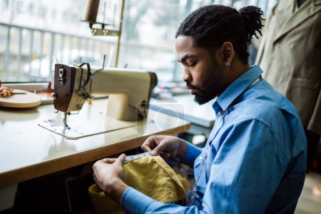 Téléchargez les photos : Homme afro-américain créateur de mode, sur mesure tissu de mesure dans son atelier. - en image libre de droit