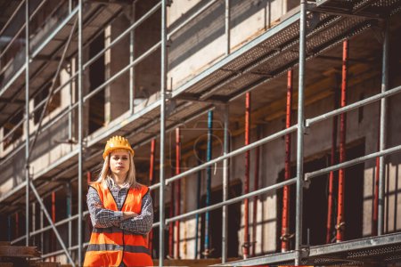 Téléchargez les photos : Architecte femme heureuse sur le chantier de construction dans l'industrie, la planification et l'inspection. Porter un casque et une veste de sécurité - en image libre de droit