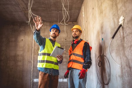 Photo for Two construction workers working together on the construction site. Visiting new building and planning new work. - Royalty Free Image