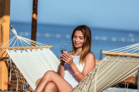Photo for Young beautiful woman using  the phone on the beach. - Royalty Free Image